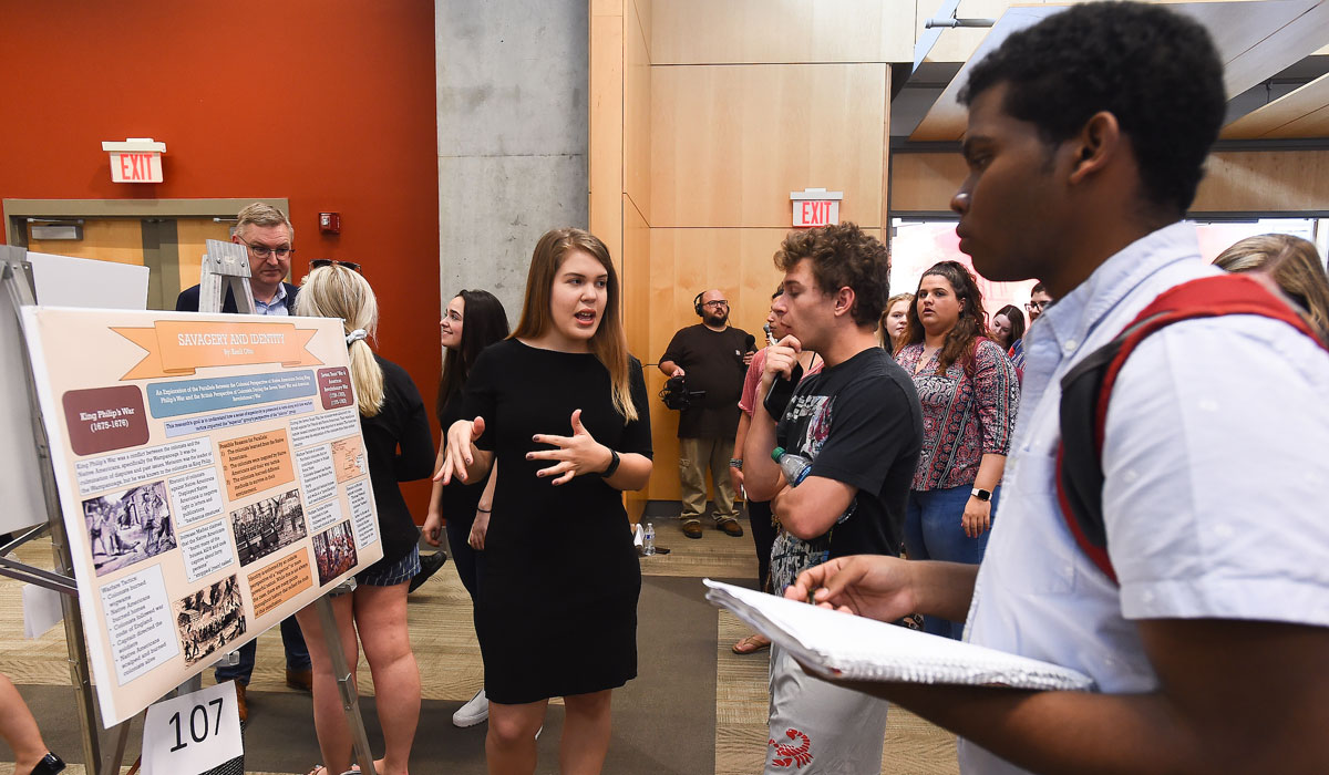 Student explaining her research poster